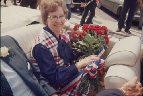 A picture of an elderly woman holding flowers in a car.