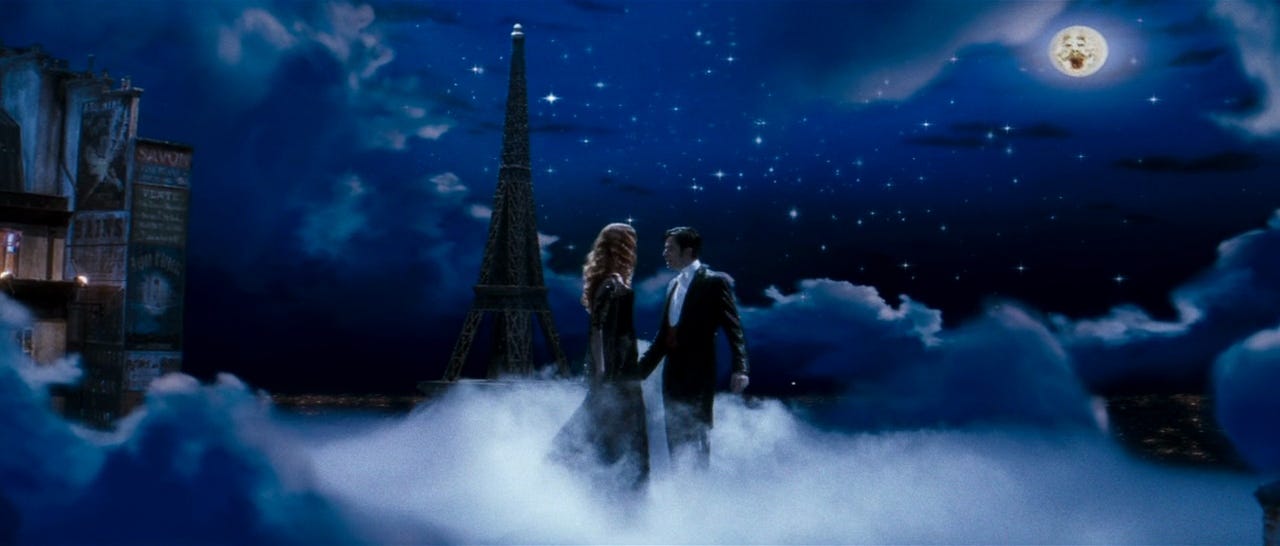 Film still from Moulin Rouge. Nicole Kidman and Ewan McGregor stand in the clouds against a starlit sky.