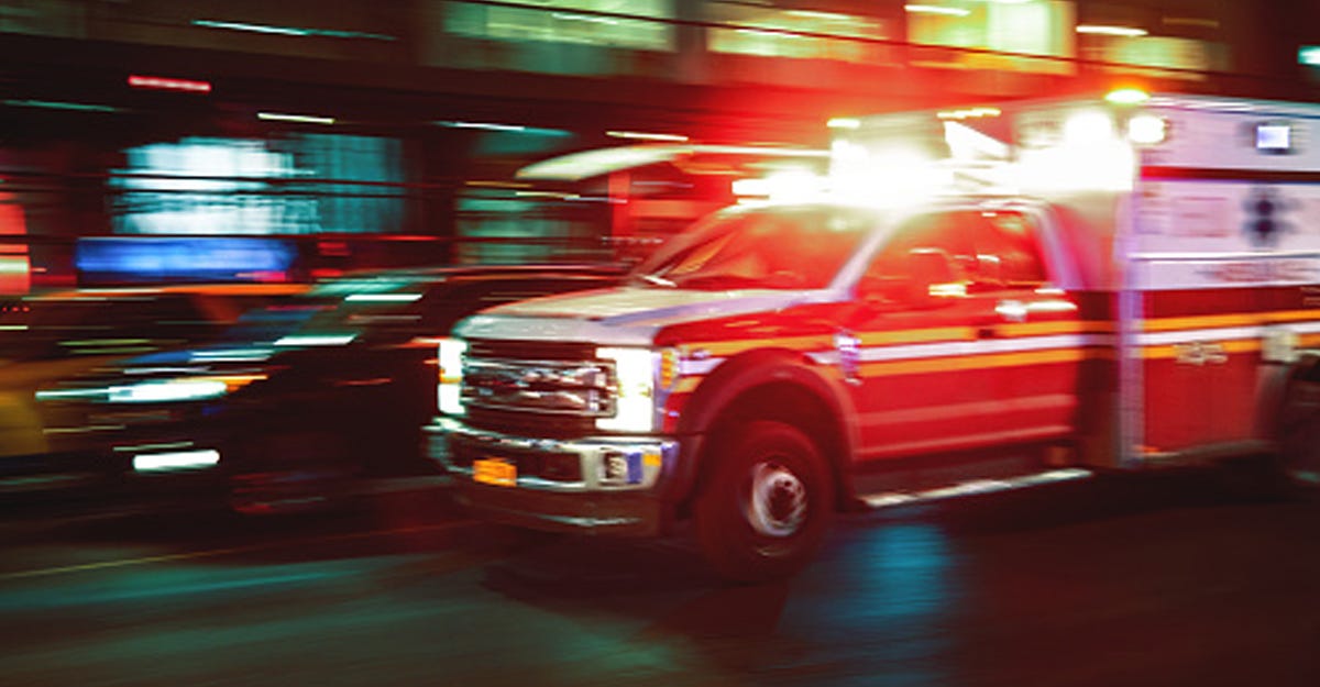 An image of an ambulance at night with the lights blurred into streaks. 