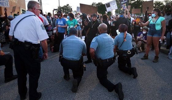 Police officers from Ferguson, Mo., join protesters to remember George Floyd by taking a knee in the parking lot of the police station on Saturday, May 30, 2020. The demonstration was prompted by the death of Floyd, a black man who was killed in police custody in Minneapolis on May 25. (Robert Cohen/St. Louis Post-Dispatch via AP)