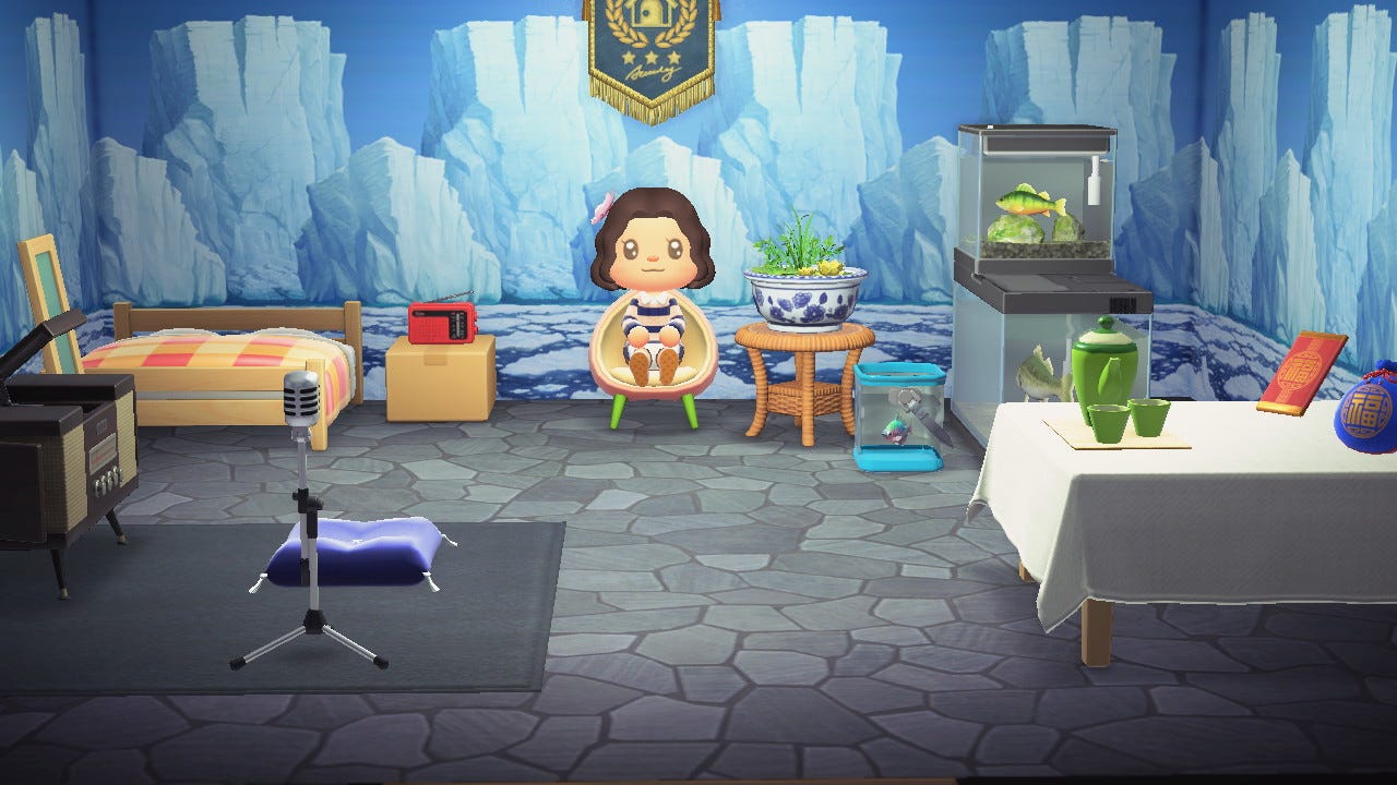 A female character sitting on a peach chair in a room decorated with a bed, a table, fish tanks, and other decor.