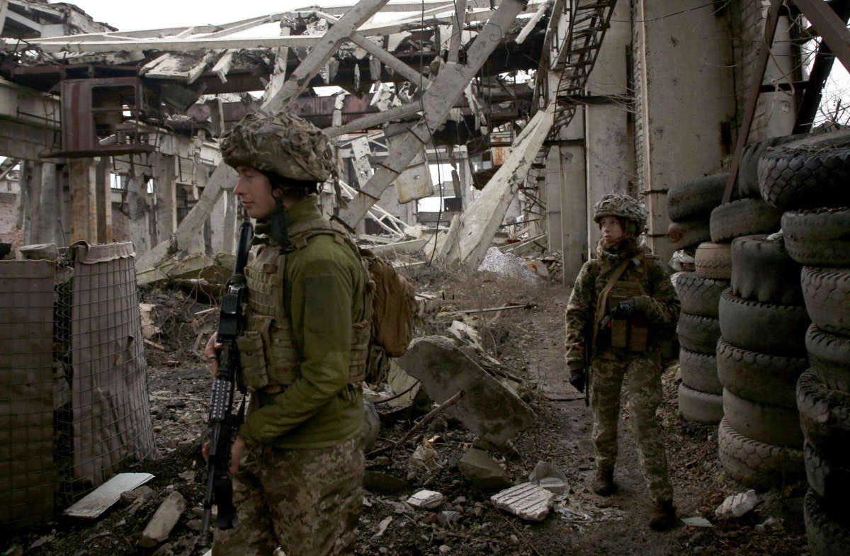 Two Ukrainian soldiers walking through rubble on front lines.
