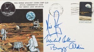 A postcard with a painting of an astronaut on the moon and signatures in blue on the side