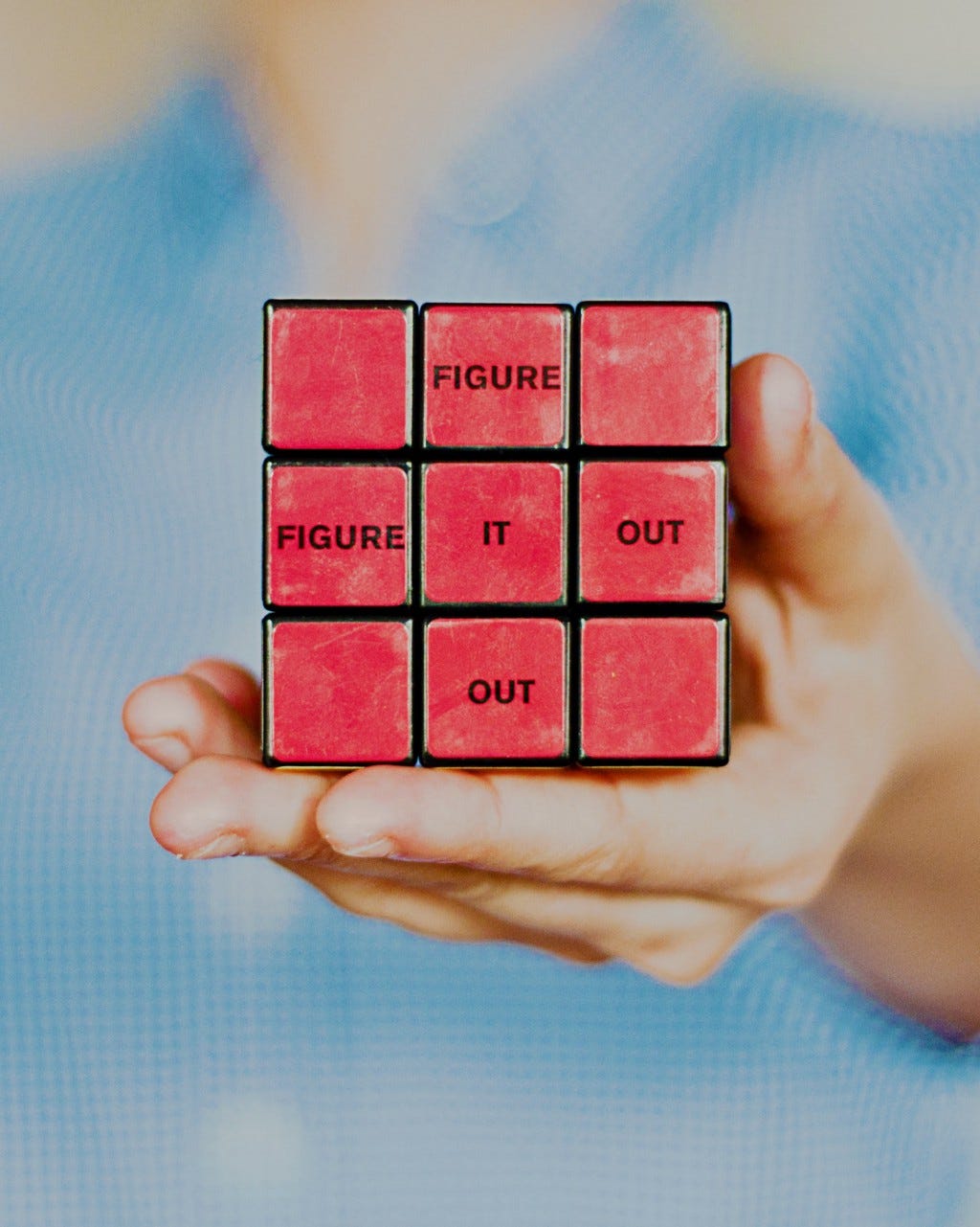 Person holding a solved rubik’s cube with the words “figure it out”.