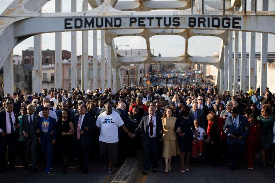 Hundreds of marchers, led by Vice President Kamala Harris and several civil-rights leaders, cross a bridge.