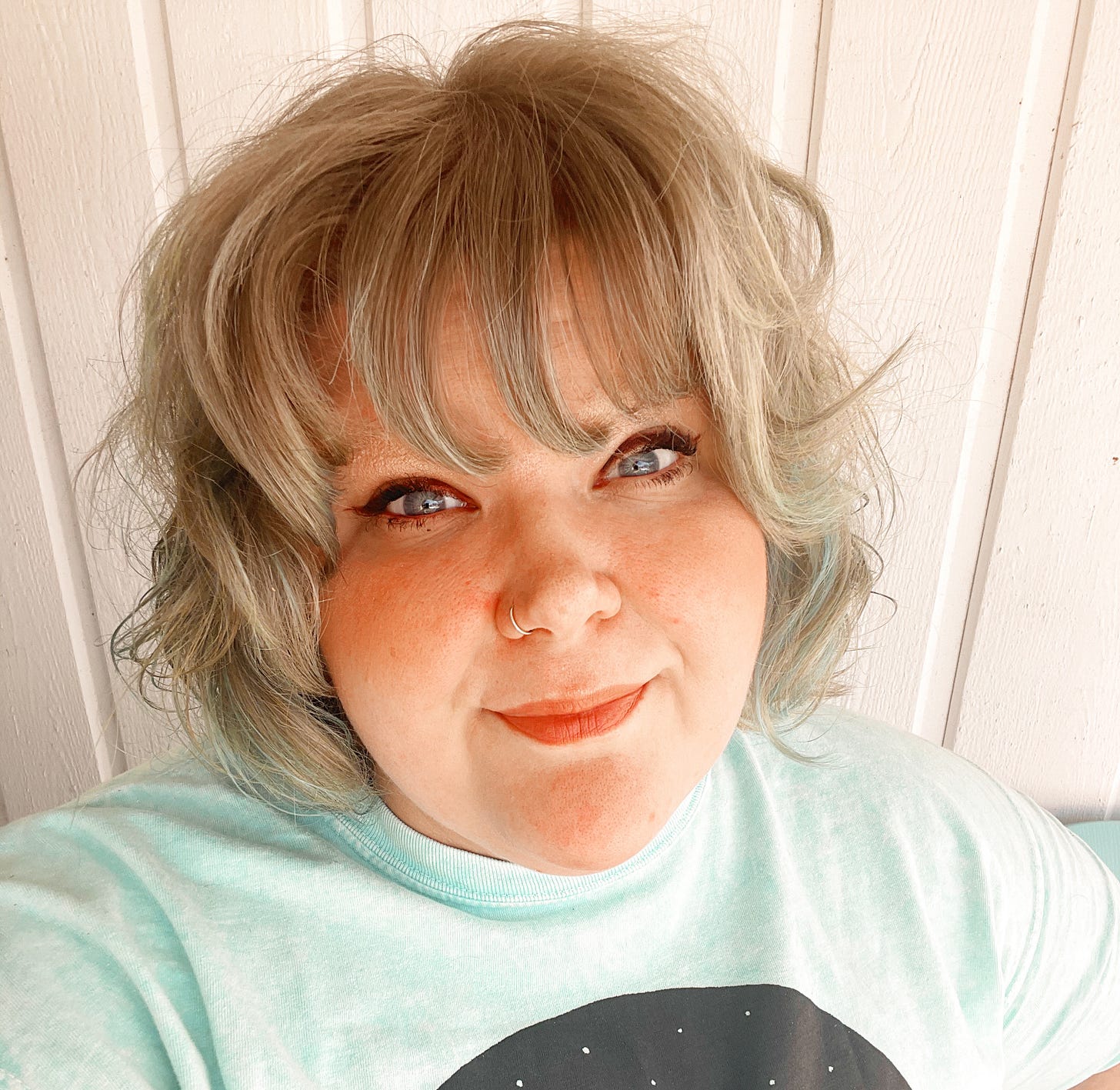 Chelsea poses in a light blue Grateful Dead shirt and sports a gray and blue bob.