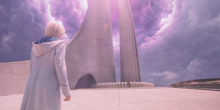 This image shows a gateway portal and the Timeless Child in the far distance. The Thirteenth Doctor (played by Jodie Whittaker), with her back to camera, watches the portal and the child. This image shows a gateway portal and the Timeless Child in the far distance. The Thirteenth Doctor (played by Jodie Whittaker), with her back to camera, watches the portal and the child.