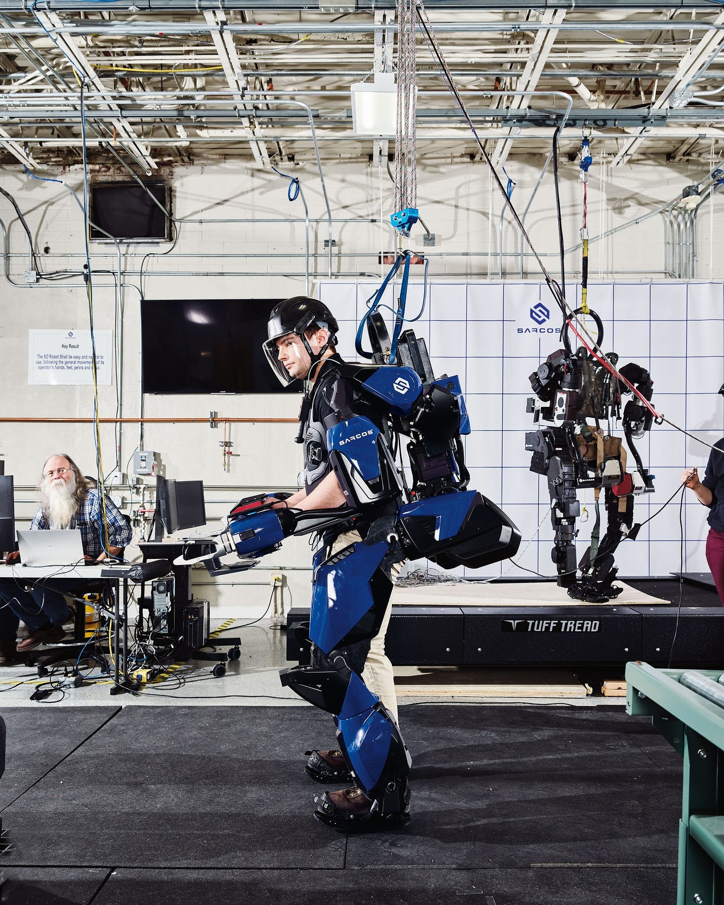 A man stands wearing a robotic exoskeleton