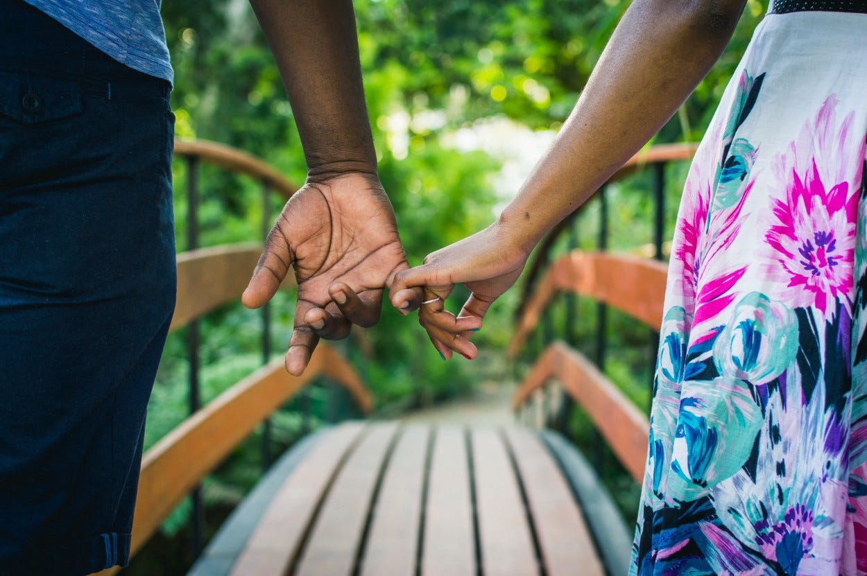 A couple holds hands on a bridge.