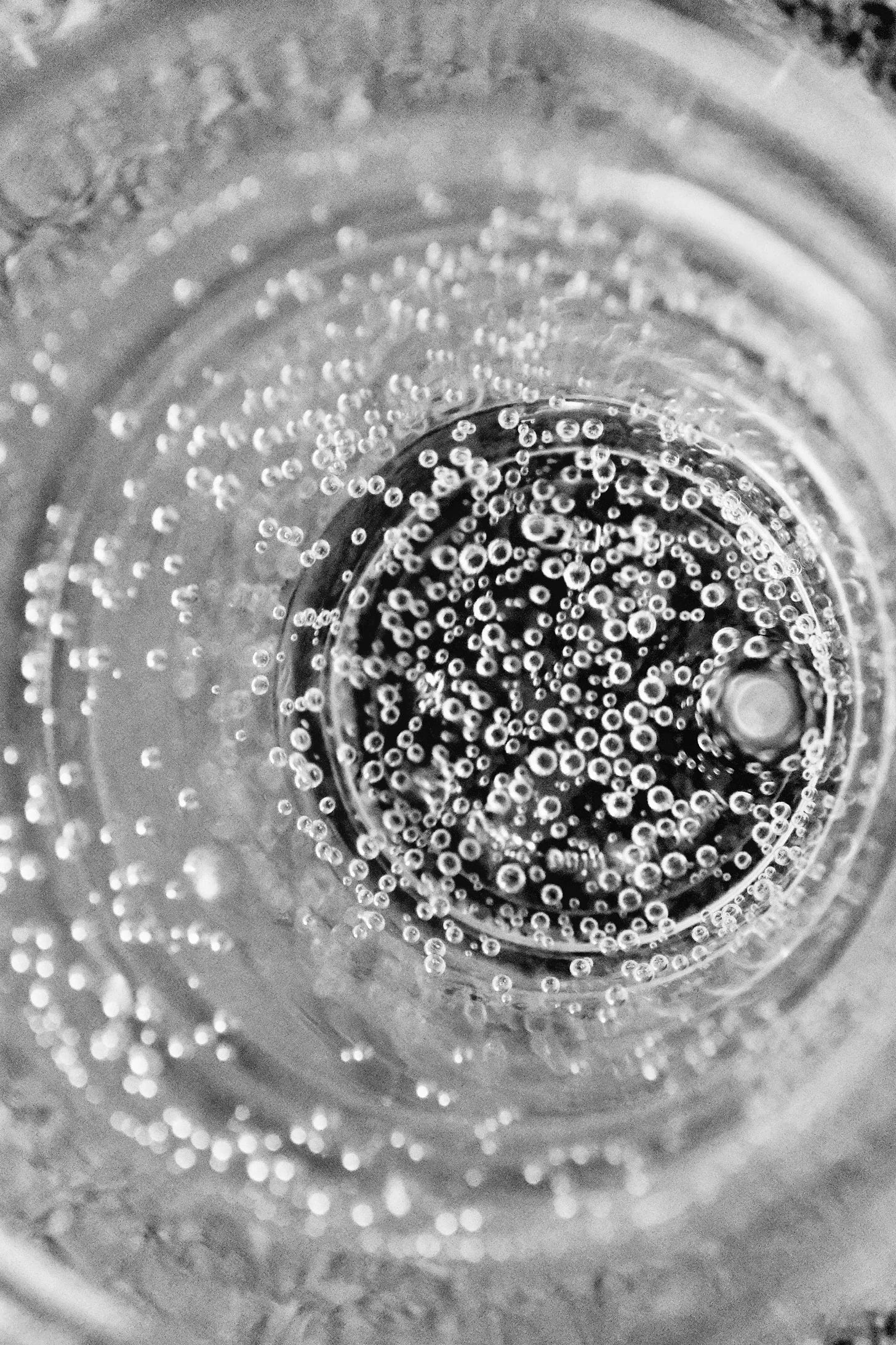 A black and white photo of a swirly abstract surface with lots of little bubbles covering a black hole in the middle.