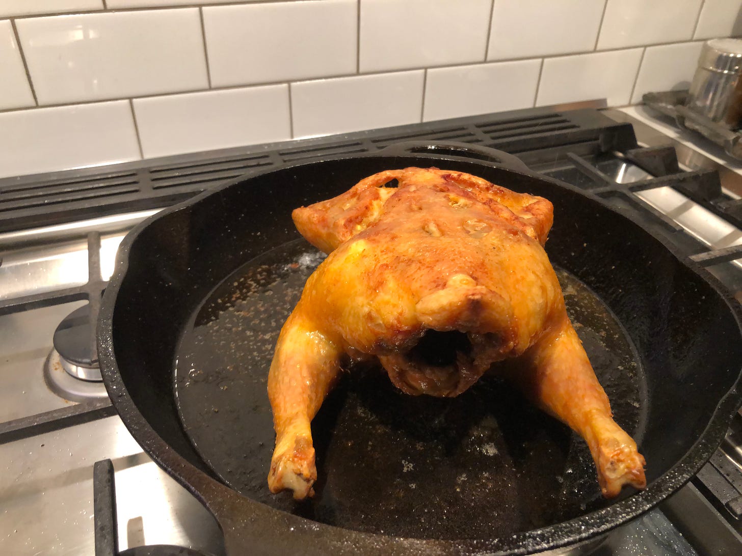Chicken, now flipped breast-side down, in pan