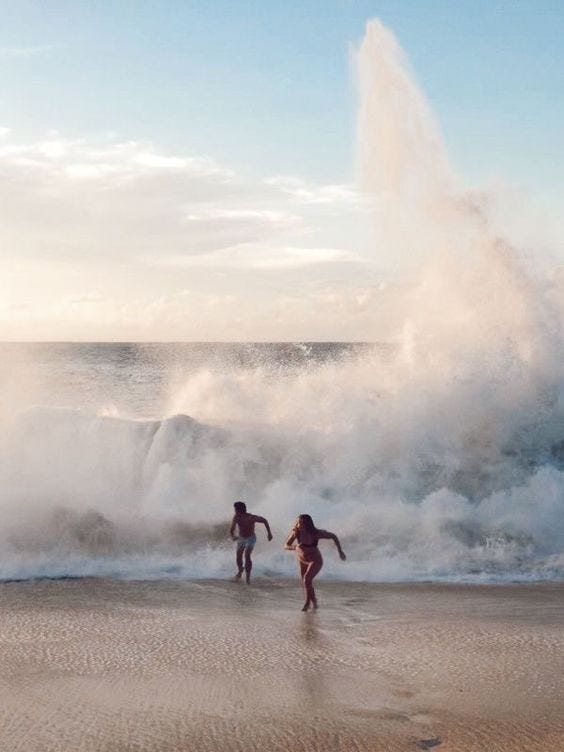 duas pessoas correndo de uma onda