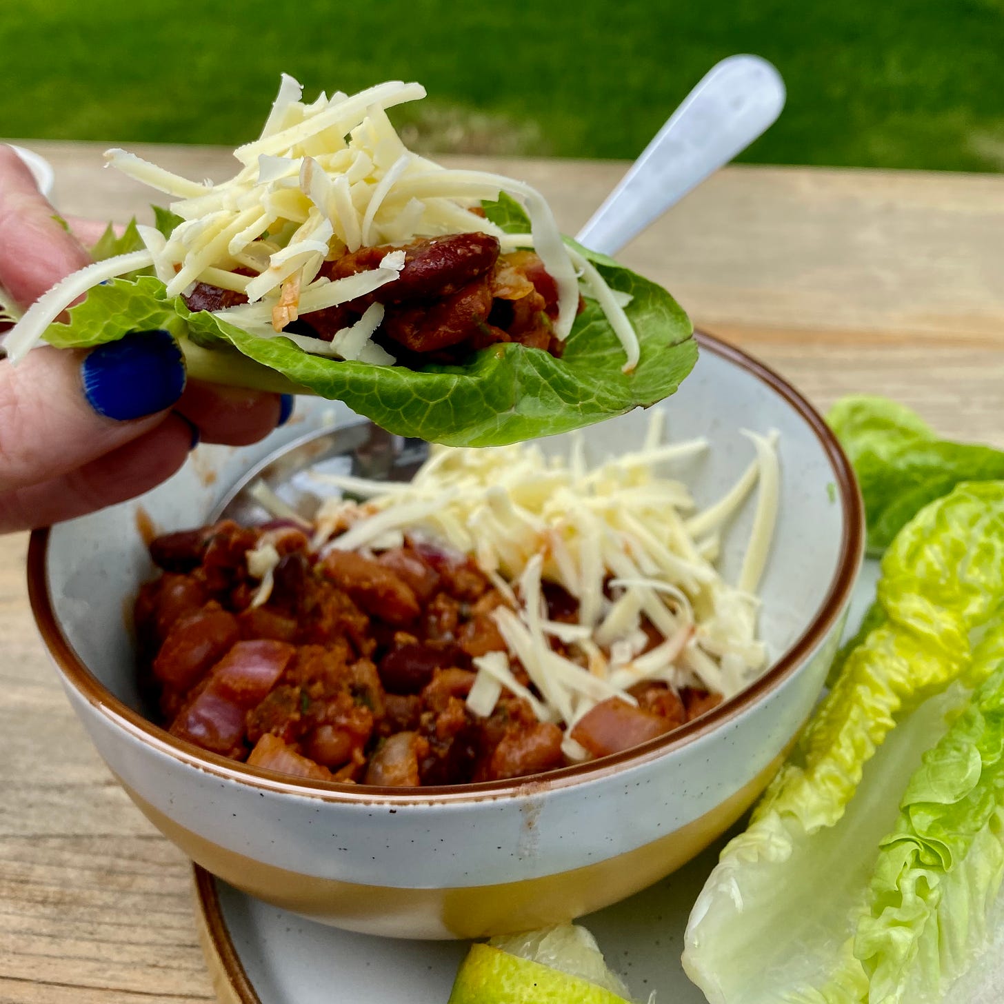 Bowl of taco bean chilli, with grated cheese and lettuce leaves