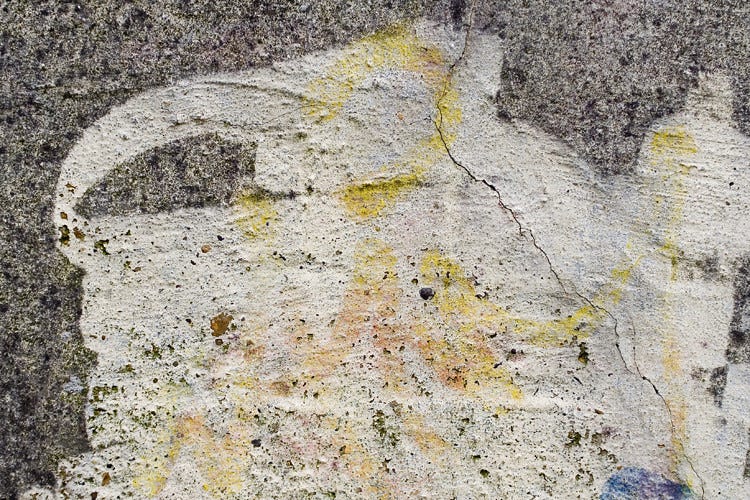 A photo of a gray wall with white paint used to erase graffiti on it. A photo of a gray wall with white paint used to erase graffiti on it.