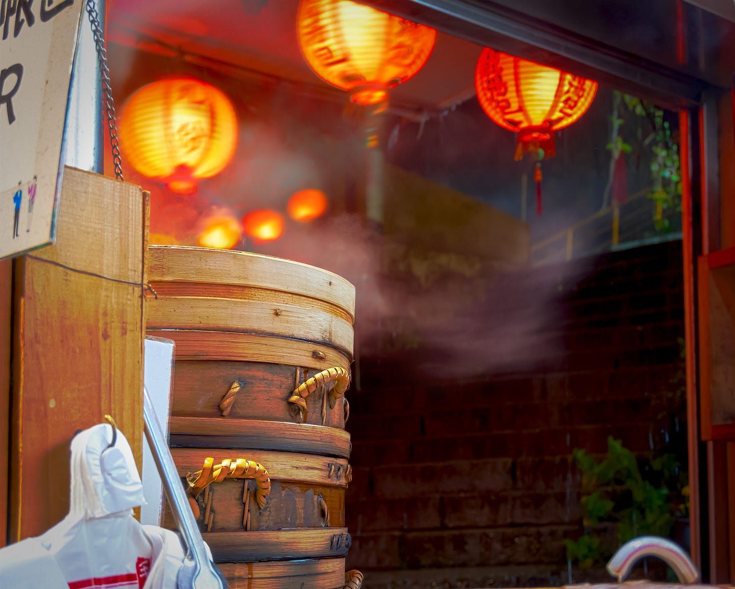 Steam billows from bamboo dumpling steamers and red lanterns wave in the wind of a nighttime rainstorm in Jiufen 九份