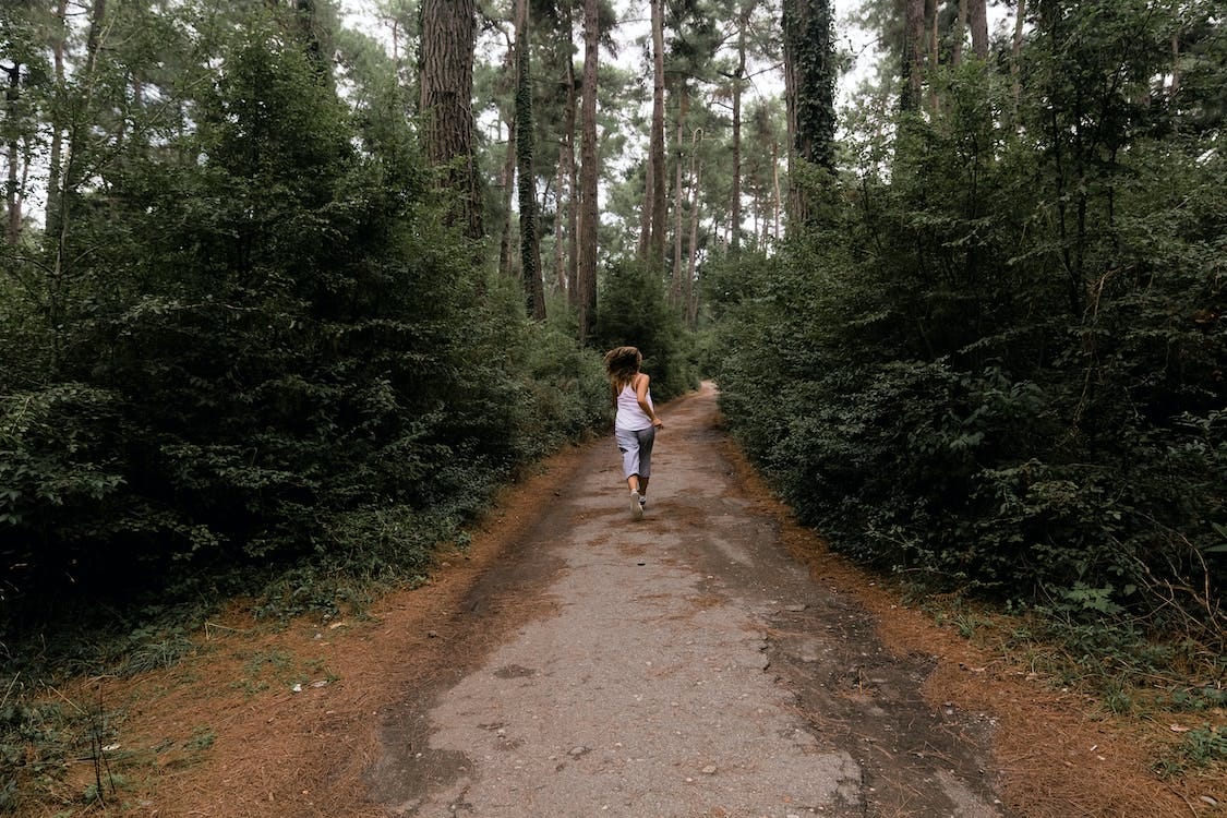 Free Woman Running in a Unpaved Pathway in  the Forest Stock Photo