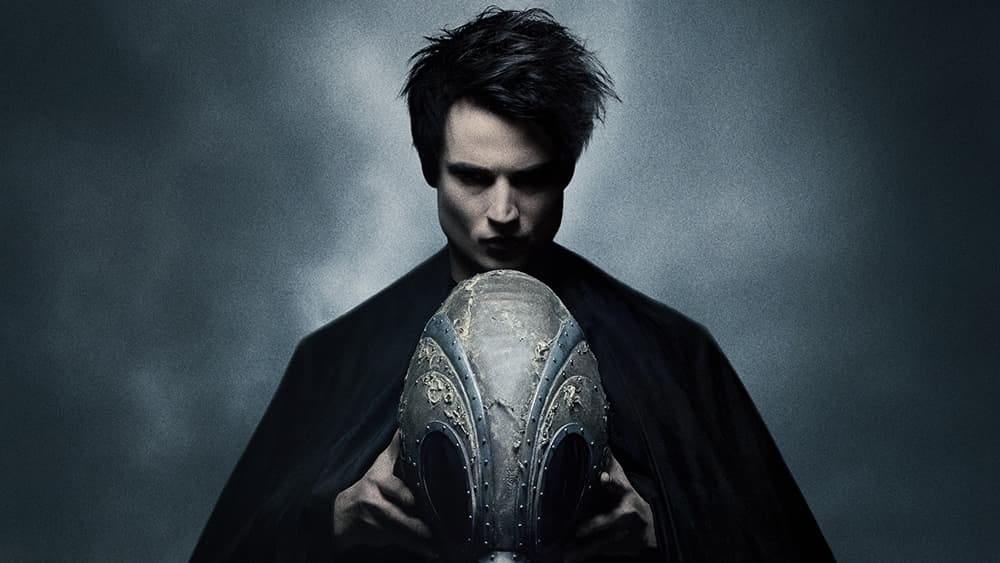 Tom Sturridge as Morpheus, holding a strange device against a moody background