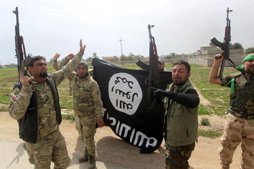 Members of the Iraqi paramilitary Popular Mobilization units celebrate with a flag of the Islamic State (ISIS) group after retaking the village of Albu Ajil, near the city of Tikrit, from the jihadist group, on March 9, 2015. (Photo: AHMAD AL-RUBAYE/AFP/Getty Images)