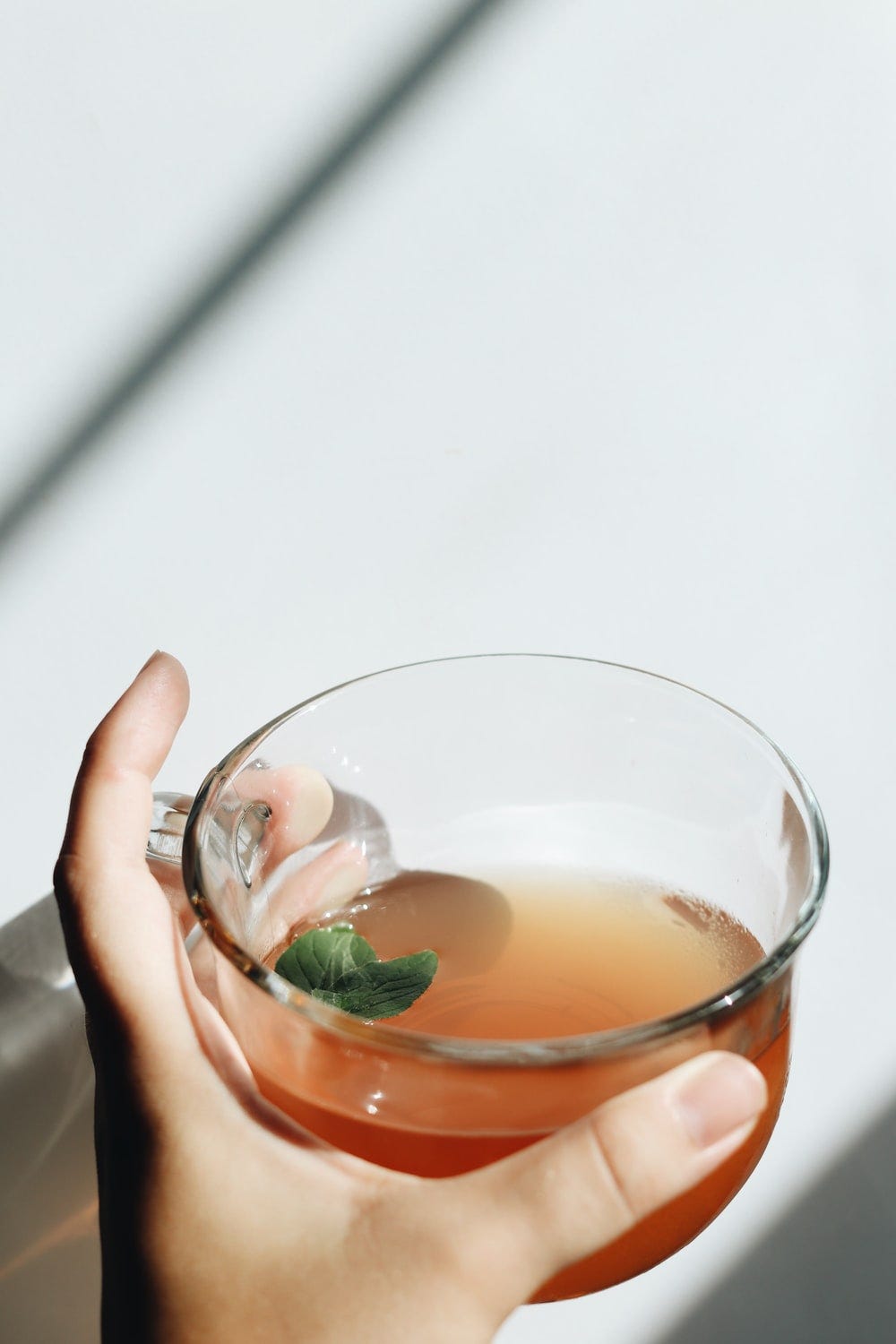 person holding clear drinking glass with brown liquid person holding clear drinking glass with brown liquid