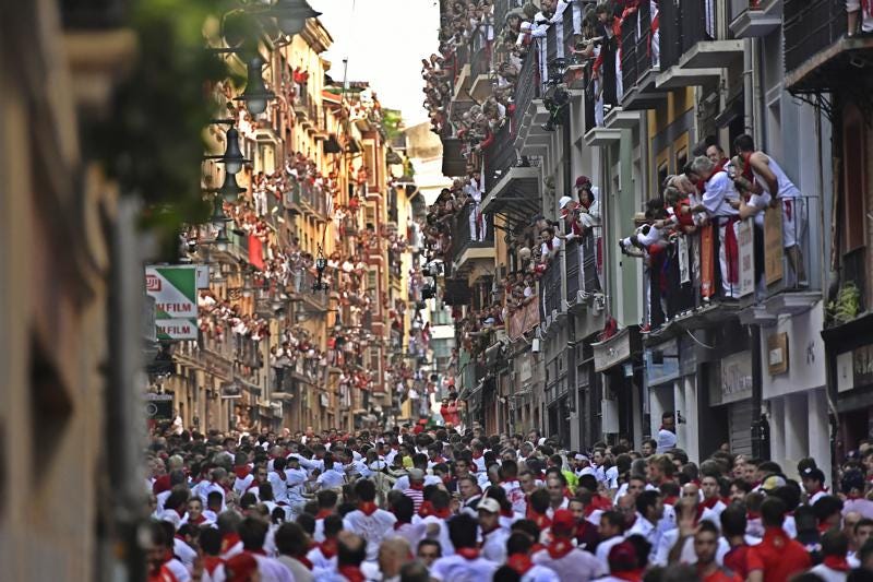 People run through the streets ahead of fighting bulls and steers during the first day of the running of the bulls at the San Fermin Festival in Pamplona, northern Spain, Thursday, July 7, 2022. Revelers from around the world flock to Pamplona every year for nine days of uninterrupted partying in Pamplona's famed running of the bulls festival which was suspended for the past two years because of the coronavirus pandemic. (AP Photo/Alvaro Barrientos)