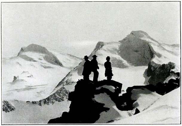 Strahlhorn - Allalinhorn. Photo by Aubrey Le Blond. Black figures on a mountain peak.
