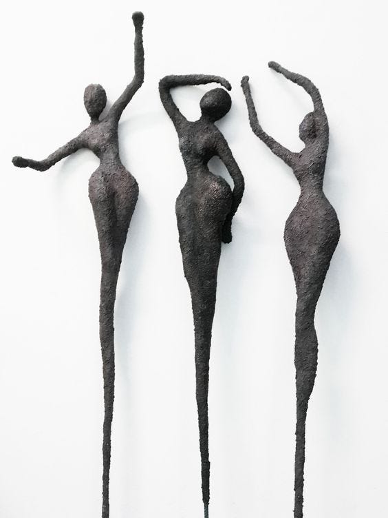 three papier-mâché female figures, reaching up, as if they are dancing