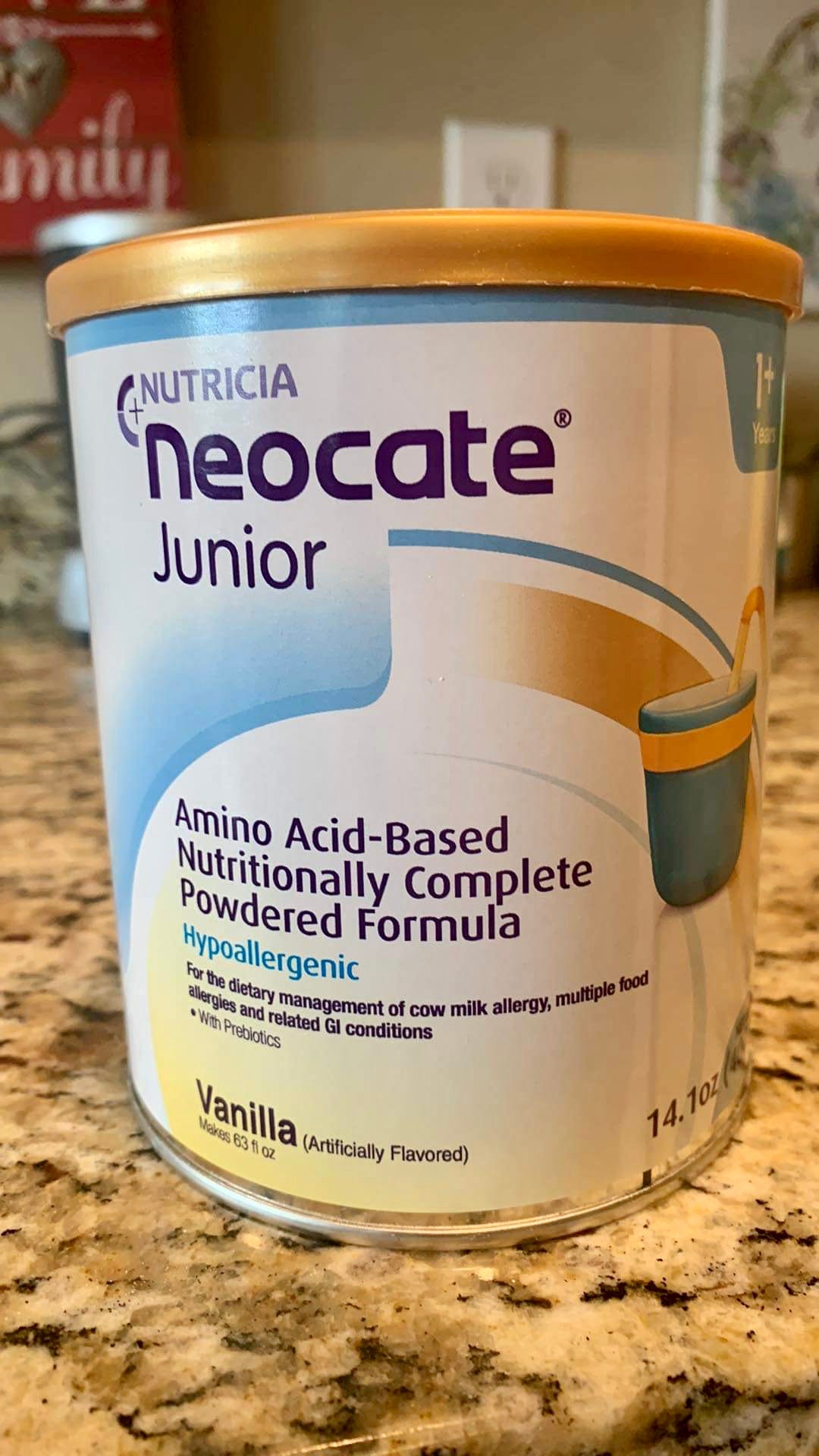 A white can of Neocate Junior sits on a marbled countertop.