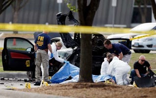 FBI crime scene investigators document the area around two deceased gunmen and their vehicle outside the Curtis Culwell Center in Garland, Texas, Monday