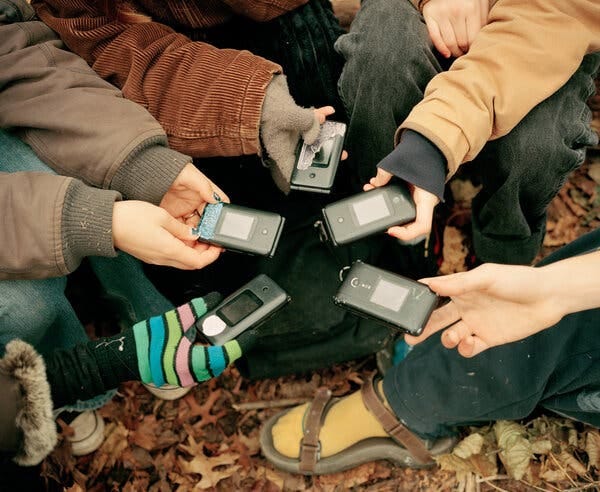 A close-up shot shows five flip phones in the hands of teenagers who belong to the Luddite Club.