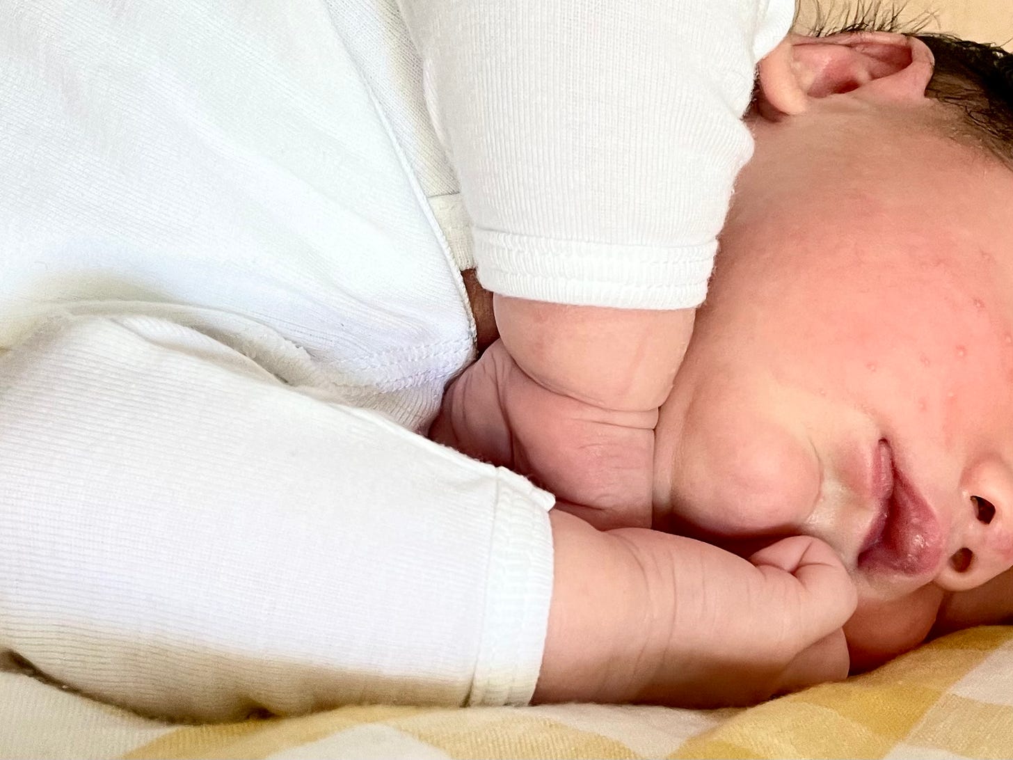 Close-up of a baby's arms, hands, chin, mouth, and nose