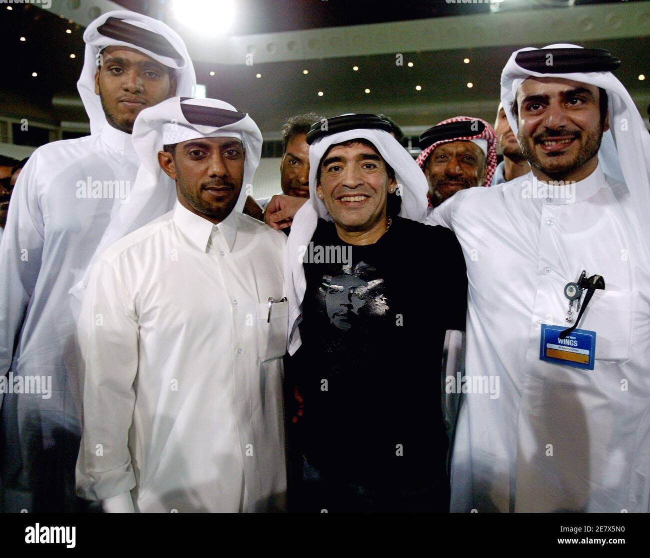 Argentina's soccer legend Diego Maradona (C) poses with Qatar fans dressed  in traditional Arabic clothes during his visit to Qatar's Alsadd Club in  Doha November 18, 2005. Maradona and Brazil's Pele were