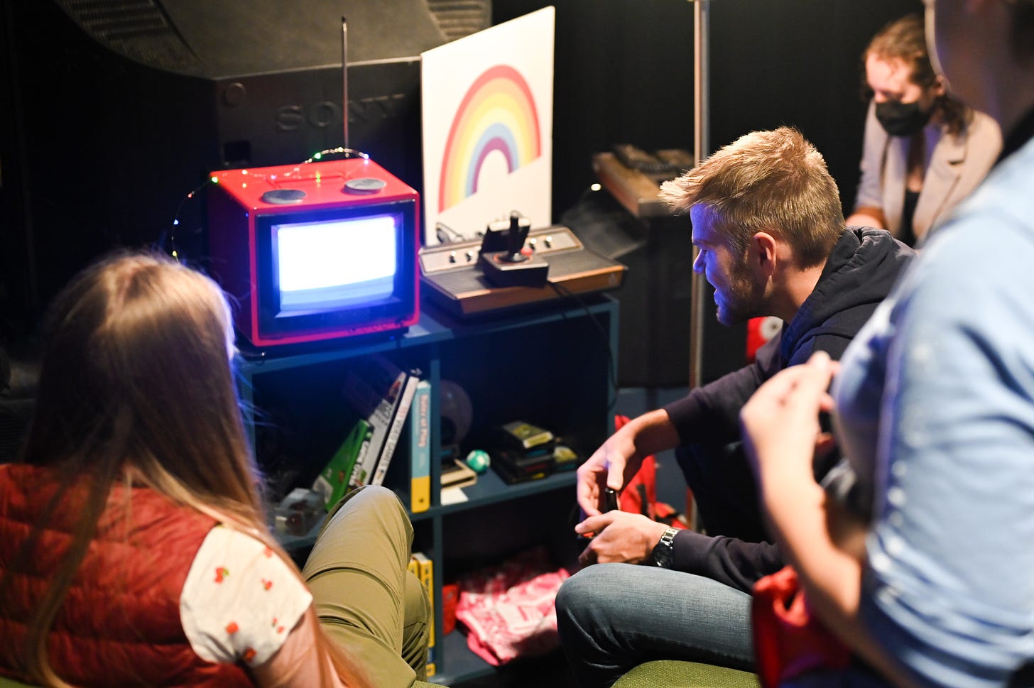 group of people playing video games on a tiny tv set