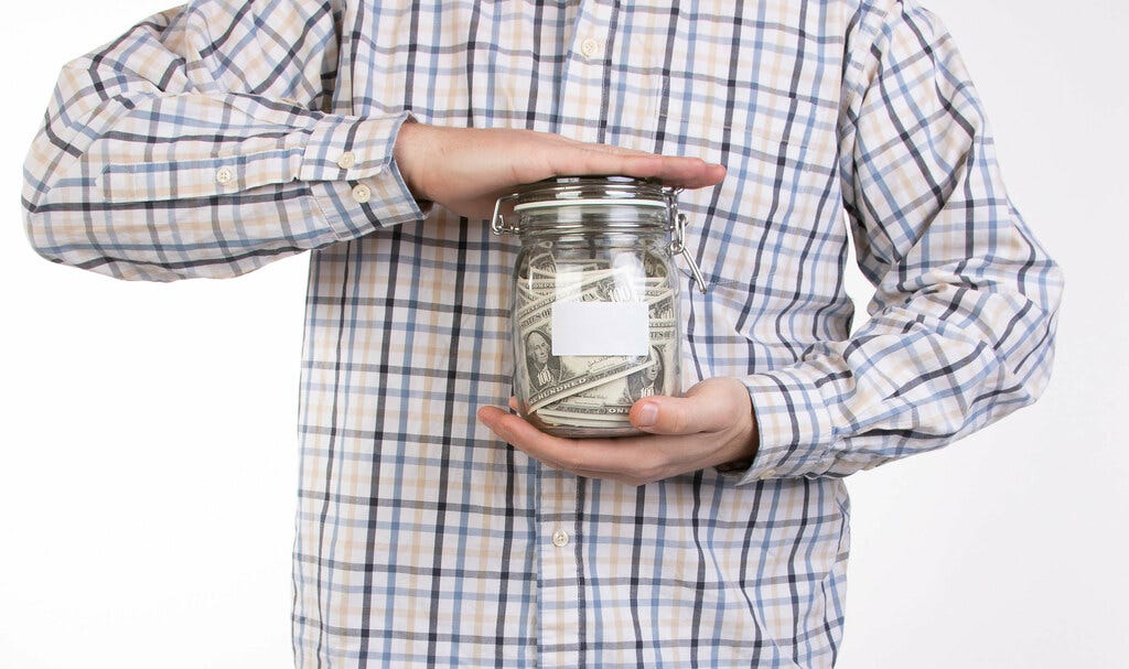 "Man in shirt holding money jar" by wuestenigel is marked with CC BY 2.0.