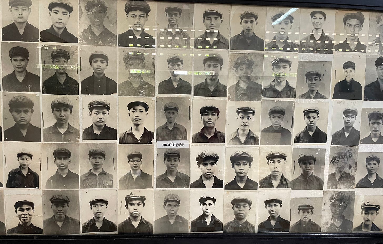 55 black and white photos of male Khmer Rouge soldiers in black shirts and caps.