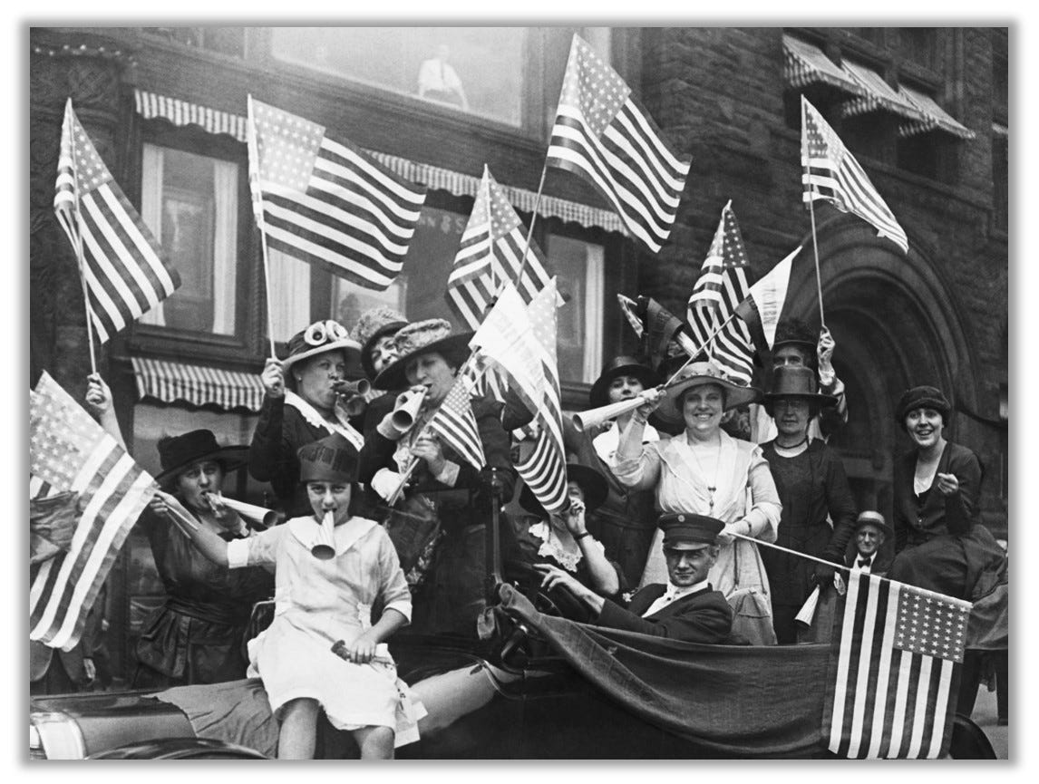 Women are pictured celebrating passage of the 19th Amendment. They are waving American flags!