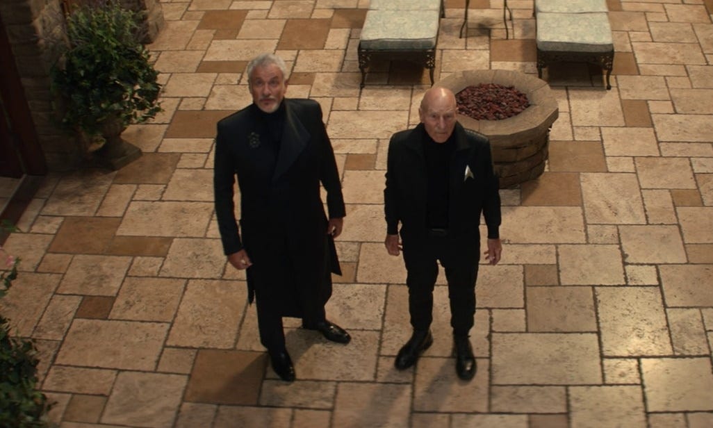 This image shows Q (played by John de Lancie) and Jean-Luc Picard (played by Patrick Stewart) standing on Château Picard's terrace and gazing upward at the sky. Q stands on the left and Picard on the right. This image shows Q (played by John de Lancie) and Jean-Luc Picard (played by Patrick Stewart) standing on Château Picard's terrace and gazing upward at the sky. Q stands on the left and Picard on the right.
