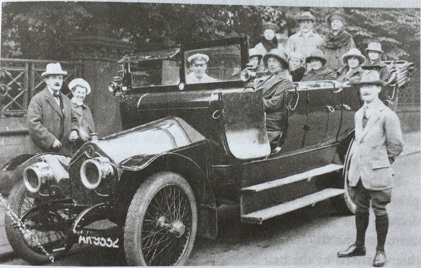A posed photo of people riding in a charabanc, or large convertible bus. black and white.