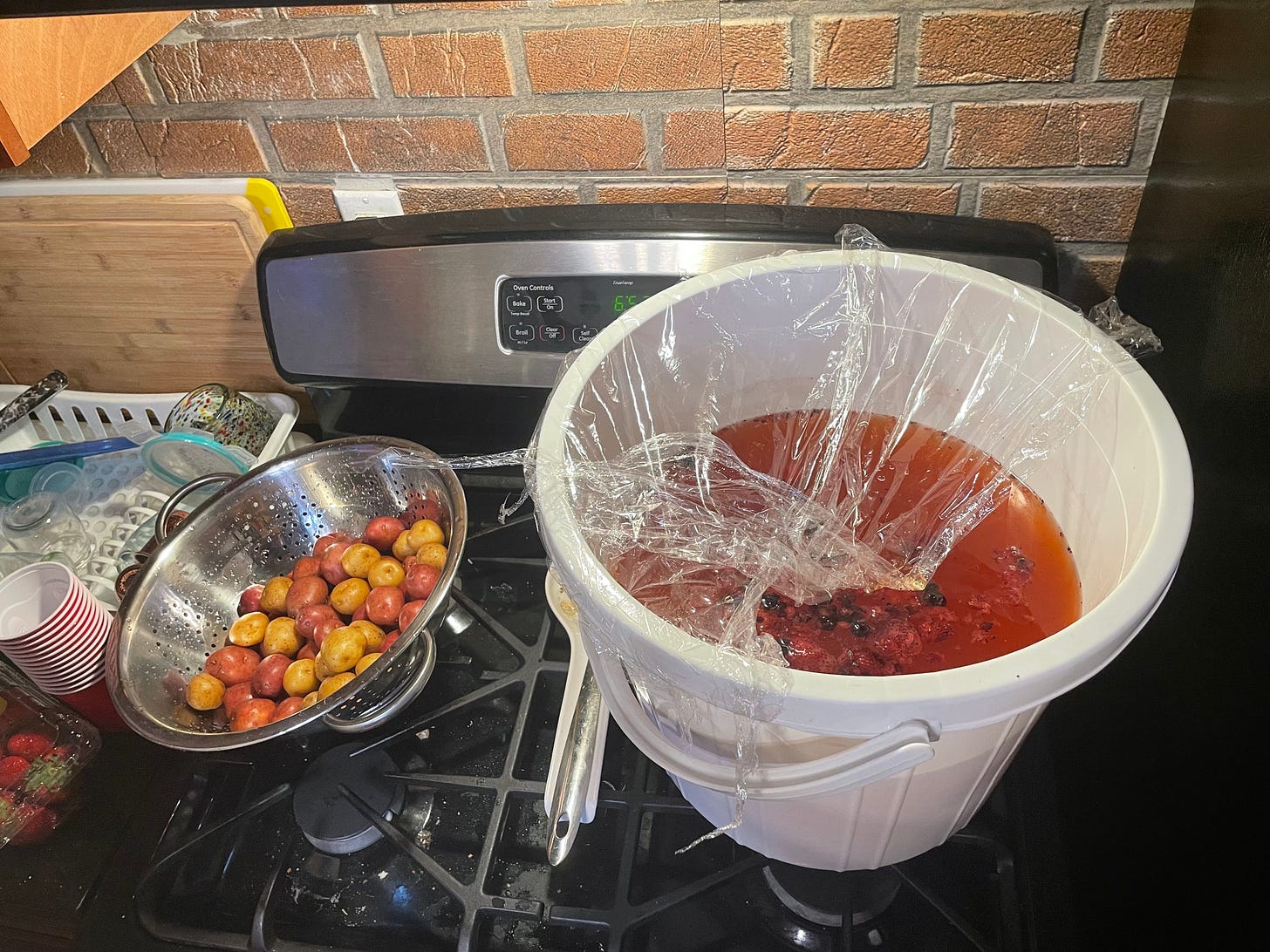colander of potatoes on stove with large bucket of berry punch