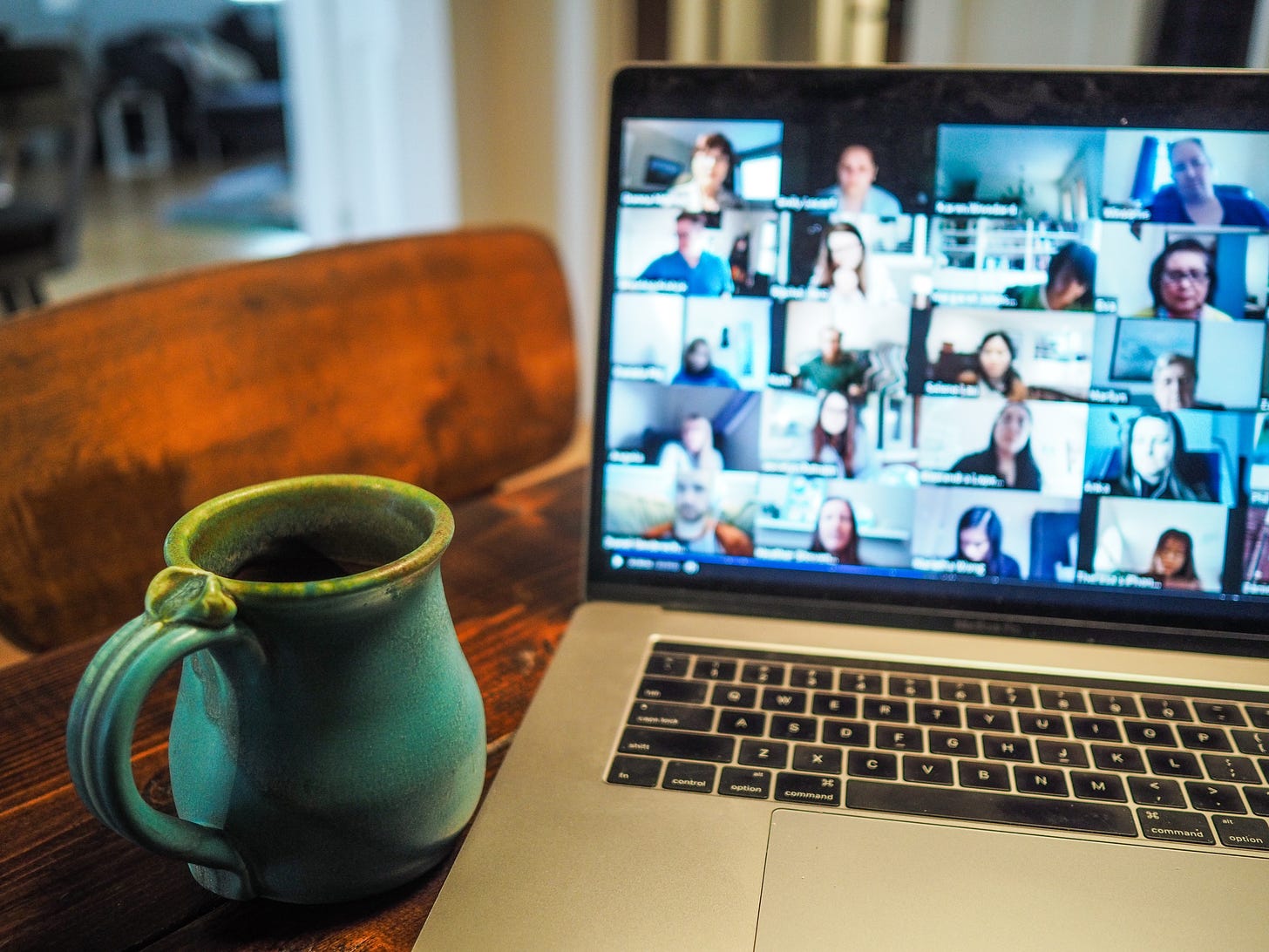 blue coffee cup placed next to a laptop screen showing a bunch of people on zoom