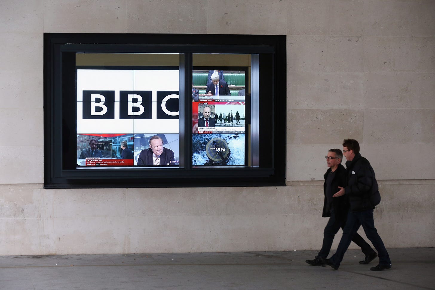 Men walk past a bank of television screens displaying BBC channels in the BBC headquarters at New Broadcasting House on November 12, 2012 in London, England. 