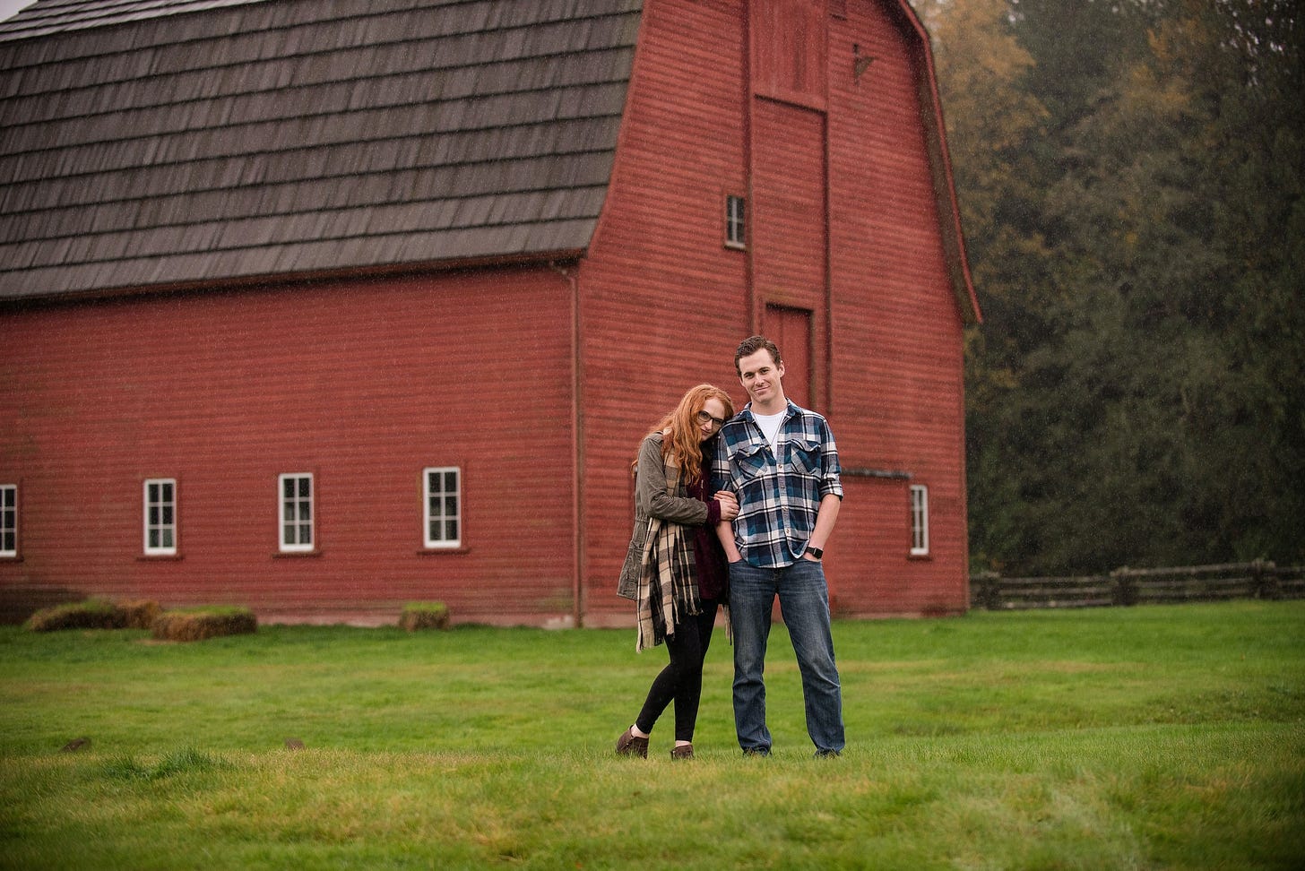 A young couple standing in front of a barn.