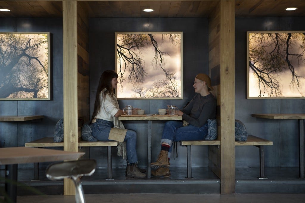 Two individuals sit at a wooden booth