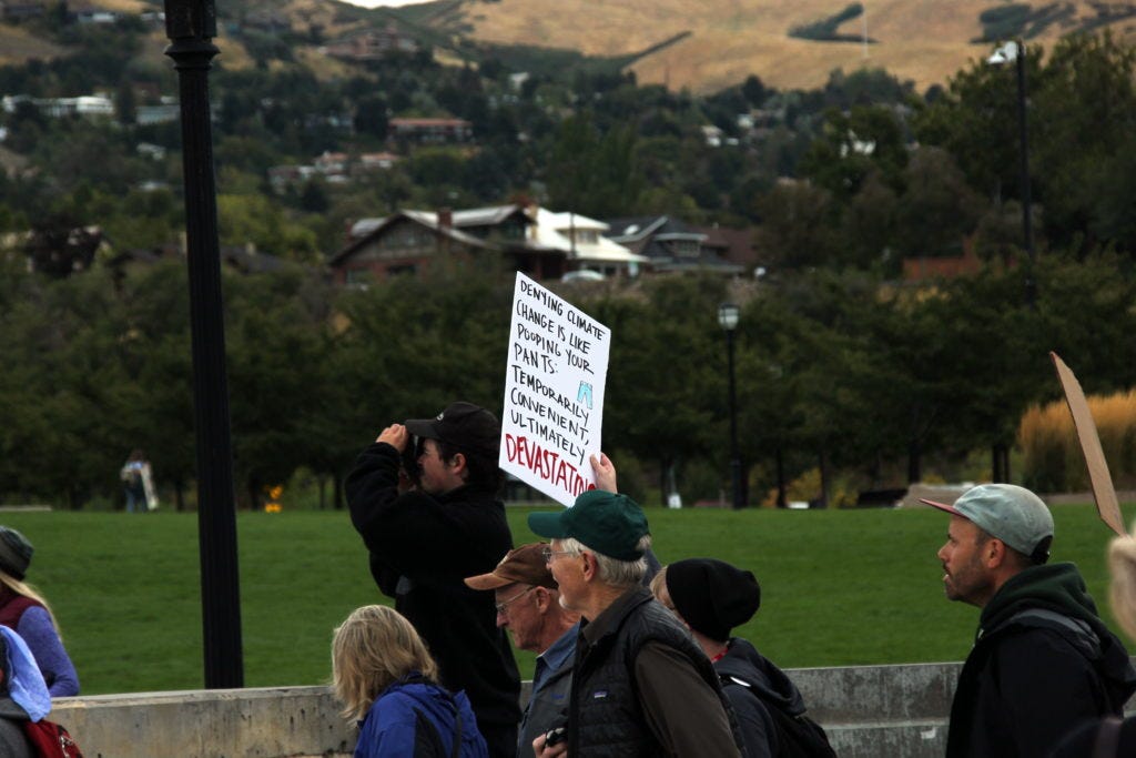 A marcher carries a sign that says, "denying climate change is like pooping in your pants: initially convenient, ultimately devastating.