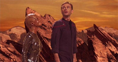This image shows a Xyrillian engineer named Ah'Len (played by Julianne Christie) and Commander Trip Tucker (played by Connor Trinneer) standing in a rocky Xyrillian holographic environment. Tucker is amazed by what he sees. This image shows a Xyrillian engineer named Ah'Len (played by Julianne Christie) and Commander Trip Tucker (played by Connor Trinneer) standing in a rocky Xyrillian holographic environment. Tucker is amazed by what he sees.