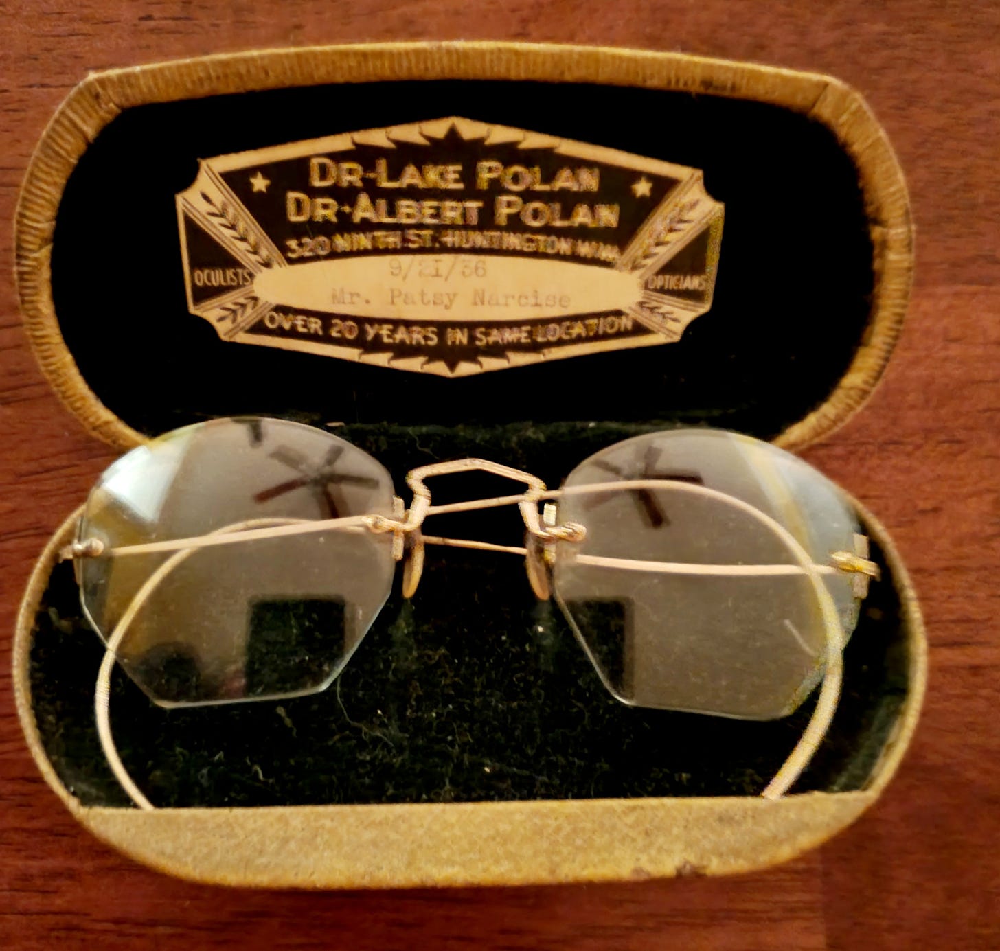 An old glasses case with a set of rimless glasses with th name and addresses of the optician shop my great grandfather and grandfather owned. 