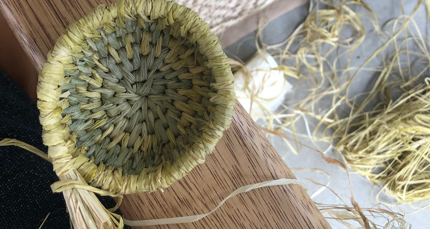 A handwoven basket in progress, made of yellow and pale green rafia