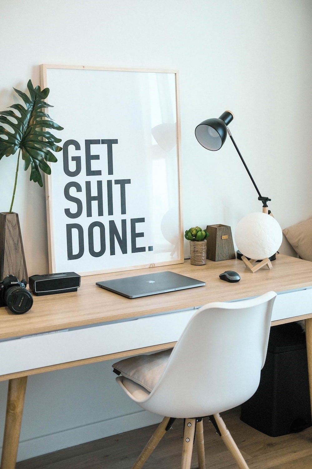 An organised desk with a sign on it which reads, "Get shit done."