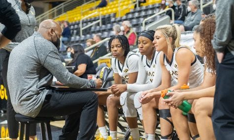 Featured is Coach Cammon drawing up a play as Berry, King and Utti observe and get ready to get back on the court after a timeout