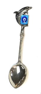 A silver, elaborate-looking spoon with a dolphine and evil eye on the handle.