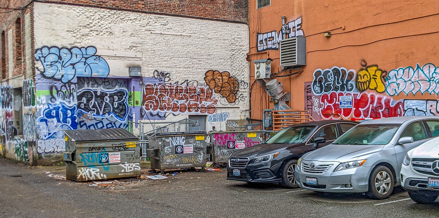 A parking lot in Seattle with various graffiti covering the walls of two buildings. 
